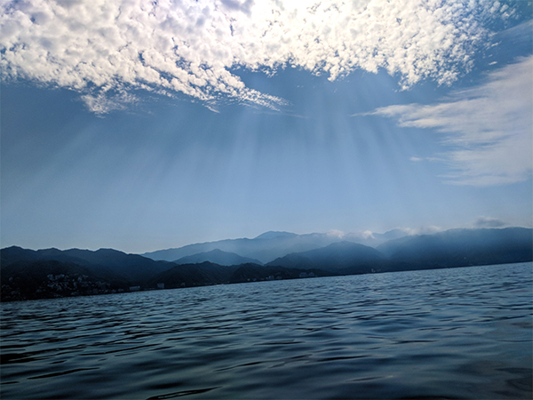 a view of the shoreline in Puerto Vallarta with sunbeams shining through the clouds.